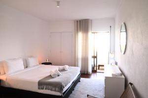 a bedroom with a bed with white sheets and a mirror at RIDE Surf Resort & Spa Peniche in Peniche +70 photos