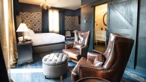 a hotel room with a bed and two leather chairs at Midnight Sun, a Coast Hotel in Dawson City