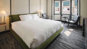 a large bed in a hotel room with a desk at Midnight Sun, a Coast Hotel in Dawson City
