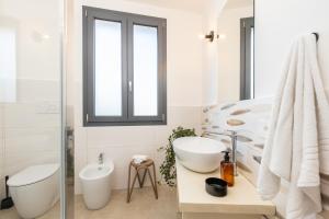 a white bathroom with a sink and a toilet at Via Tirso Rooms & Studio in Tortolì +53 photos