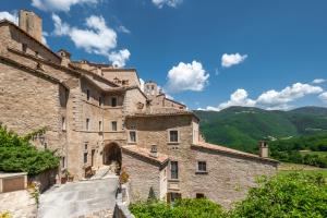 an old stone building with mountains in the background at Castello Di Postignano Relais in Sellano