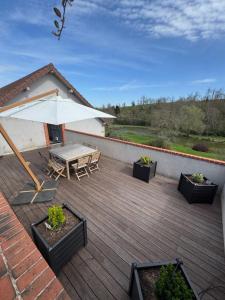 a patio with a table and an umbrella at Appartement spacieux au domaine in Coust