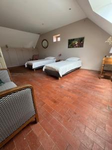 two beds in a room with a brick floor at Appartement spacieux au domaine in Coust