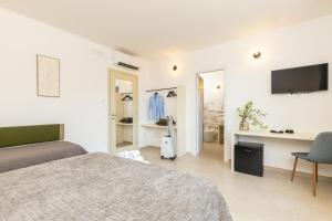 a white bedroom with a bed and a tv at Via Tirso Rooms & Studio in Tortolì