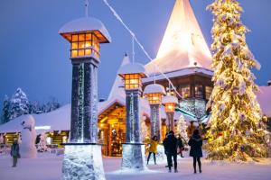 people walking in front of a building with a christmas tree at Villa Virpi in Rovaniemi