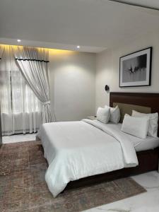 a bedroom with a large white bed and a window at Centurion Aparthotel in Abuja