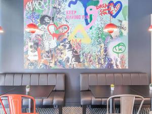 a painting on the wall of a restaurant with two tables at Hotel ibis Lisboa Alfragide in Lisbon