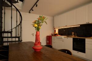 a red vase with flowers on a table in a kitchen at Unique renovated chapel in Temse