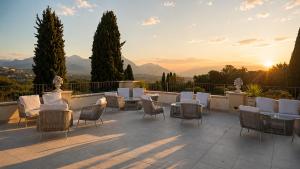 a patio with tables and chairs and the sunset at AHG Golf Hotel Porta Del Sole in Soiano del Lago