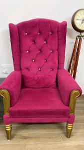 a pink chair in a room with a clock at Dimond Villa in Greater Noida +1 photo