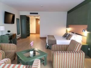 a hotel room with a bed and two chairs and a table at Hotel Naval Sestao in Sestao