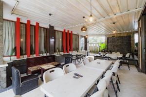 a restaurant with white tables and chairs and red walls at Urbanview My Grand Hotel Bogor in Brujul