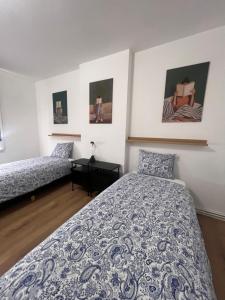 a bedroom with two beds and paintings on the wall at Victoria II Parking GRATUIT in Boussu