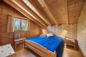 a bedroom in a log cabin with a bed and a chair at Chalet Siesta OG in Bellwald