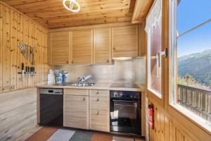 a kitchen with wooden cabinets and a window with a view at Chalet Siesta OG in Bellwald +10 photos