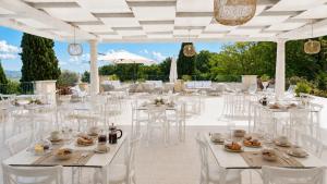 a banquet hall with white tables and chairs at AHG Golf Hotel Porta Del Sole in Soiano del Lago