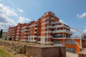 a large apartment building in front of a brick wall at Антична панорама in Hisarya