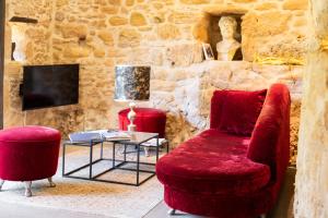 a living room with a red chair and a table at Domaine de Cantegrel - Gîtes de Charme et Suite Troglodyte en Périgord in Vitrac