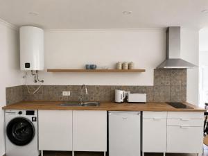 a kitchen with white cabinets and a washing machine at The Nook II, Lourinha in Lourinhã