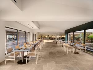 a dining room with tables and chairs and windows at Mangia's Costa Ragusa Borgo - New Opening in Scoglitti