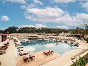 a pool with lounge chairs and umbrellas at a resort at Mangia's Costa Ragusa Borgo - New Opening in Scoglitti