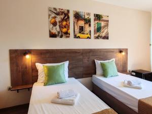 two beds in a room with paintings on the wall at Hotel Sorbona in Varna City