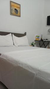 a white bed with white pillows in a bedroom at Js Immobilier in Abidjan