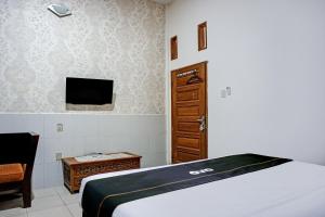 a bedroom with a bed and a tv and a chair at Hotel O Kuta Alam Near Masjid Oman Al-Makmur Formerly Daka Hotel in Lheue