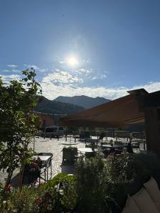 a patio with tables and chairs with the sun in the sky at Ostan Hôtel Boutique in Roquebillière