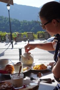 a woman is standing at a table with food at Ostan Hôtel Boutique in Roquebillière