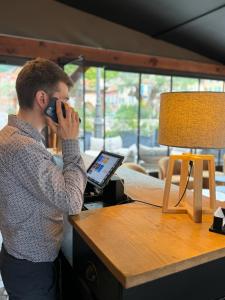 a man talking on a cell phone next to a table with a laptop at Ostan Hôtel Boutique in Roquebillière +12 photos