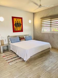 ein Schlafzimmer mit einem großen weißen Bett in einem Zimmer in der Unterkunft Hôtel Mango GI in Saly Portudal