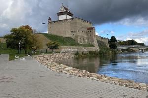 a castle with a clock tower next to a river at Border Madise Apartment, Madise tn 8, Apt 7, Narva in Narva