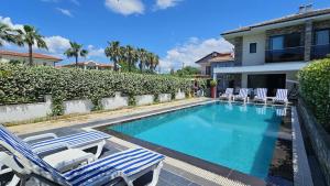 a swimming pool with lounge chairs and a house at Villa Zümrüt in Ortaca