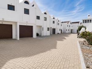 a row of white buildings on a brick driveway at Dwarskersbos,Skilliepark in Velddrif