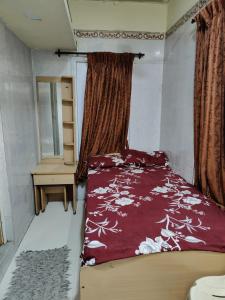 a bedroom with a bed with a red comforter at Sri Sai Lodge in Palni
