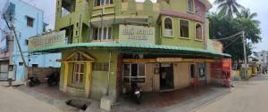 a yellow and green building on a city street at Sri Sai Lodge in Palni