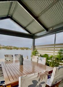 a wooden table and chairs on a deck with a view of the water at Overwater on the Murray in Murray Bridge