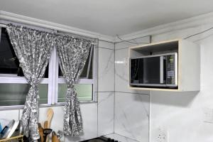 a kitchen with a microwave and a window at Goshen Lodge Goodwood in Goodwood