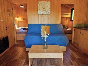 a living room with a blue couch and a table at Tiny house - Cabane sur pilotis - Etat Nature in Magnières