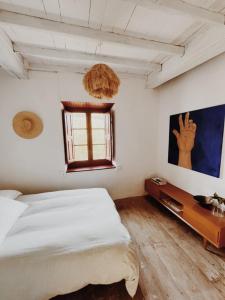 a white bedroom with a bed and a window at Cal Mengo in La Vega