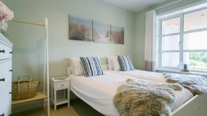 a bedroom with a large white bed with a window at Glangors in Abersoch