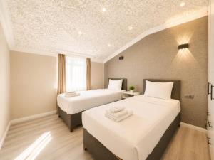 two beds in a hotel room with white sheets at Casa Florya Suites in Istanbul