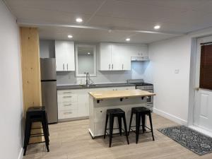a kitchen with white cabinets and bar stools at Motel Chantmartin in Tadoussac