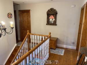 a hallway with a staircase with a clock on the wall at Room Two Stay in Corran Cross Roads +1 photo