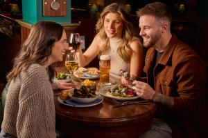 a group of people sitting around a table with food at The Seaton Lane Inn - The Inn Collection Group in Seaham