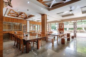 a large dining room with wooden tables and chairs at Urbanview Remington Hotel Palembang By RedDoorz in Palembang