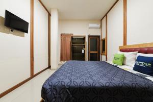 a hotel room with a bed and a flat screen tv at Urbanview Remington Hotel Palembang By RedDoorz in Palembang +19 photos