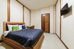 a bedroom with a bed with a laptop on it at Urbanview Remington Hotel Palembang By RedDoorz in Palembang