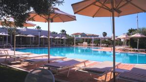 a swimming pool with lounge chairs and umbrellas at Residenze Poseidon in Le Castella
